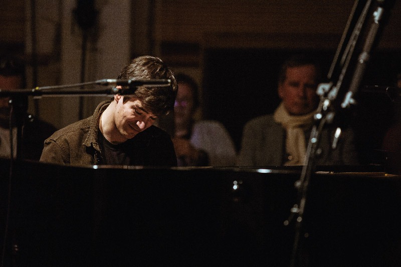 Vooraanzicht van Bram De Looze die in opperste concentratie op de piano speelt