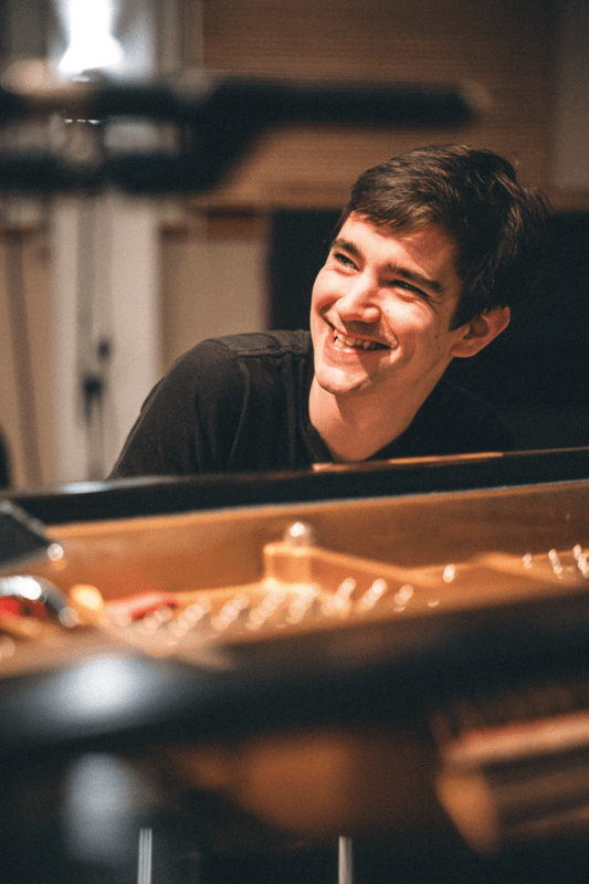 Bram De Looze is smiling behind the piano
