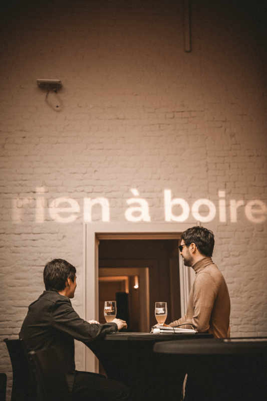 Bram De Looze et Karl Meesters boivent une bière sous les lettres illuminées 'rien à boire'