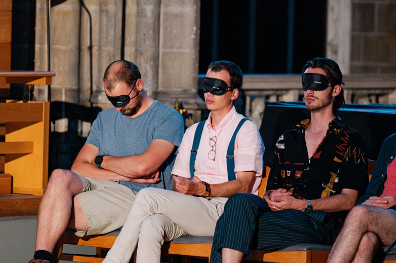 In de kerk zitten 3 personen met een oogmasker op naar het concert van Dionysos Now! te luisteren