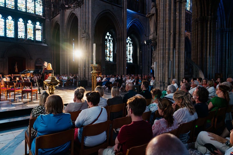 Vooraan in de kerk wordt tenor Tore Tom Denys geïnterviewd. Op de voorgrond het talrijke publiek.