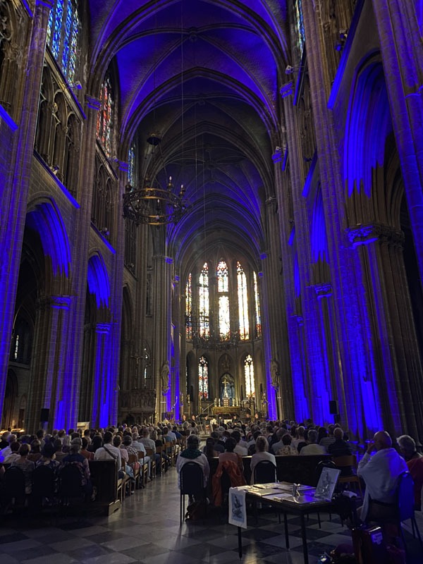 Zicht naar het altaar waar de zangers van Dionysos Now! staan. In de kerk is het donker, de constructie is met blauwe lampen verlicht.