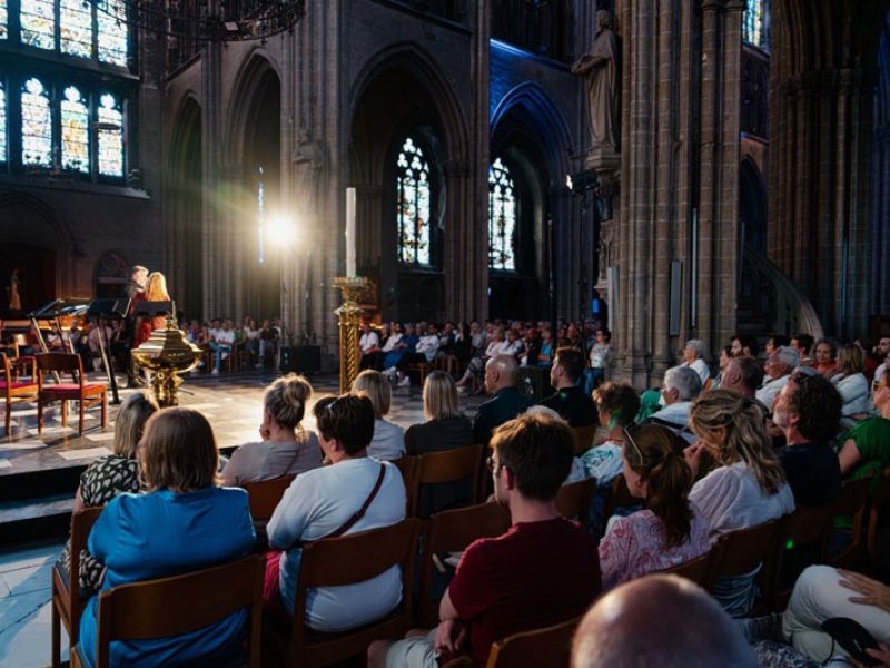 A l'avant de l'église, le ténor Tore Tom Denys est interviewé. Au premier plan, le public nombreux.