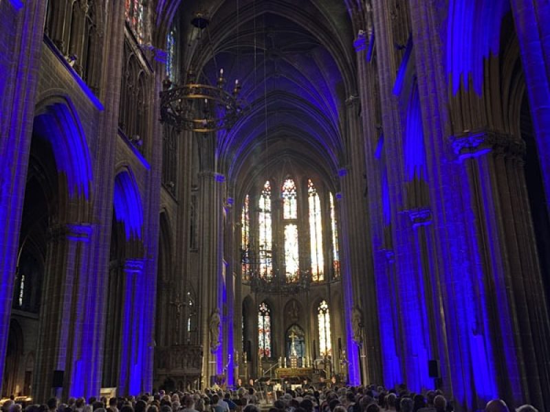 Zicht naar het altaar waar de zangers van Dionysos Now! staan. In de kerk is het donker, de constructie is met blauwe lampen verlicht.